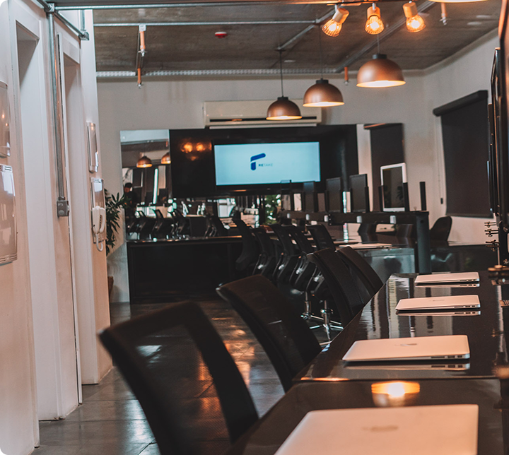 Modern office workspace with black leather chairs, wooden desks, and industrial lighting